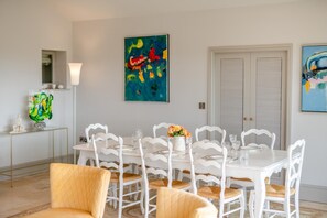 A dining area with a white table and chairs, a vase with flowers, and abstract art on the walls. - 4 Bed in Wensley (oc-t45784) (Wensley)