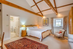 A bedroom with a large bed, a chair, a nightstand, a window with curtains, and a door leading to a bathroom. - 4 Bed in Wensley (oc-t45784) (Wensley)