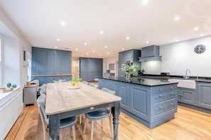 A modern kitchen with a central island, grey cabinetry, and a dining area with a wooden table and chairs. - 6 Bed in West Malling (oc-n45282) (Kings Hill)