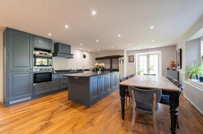 A modern kitchen with a central island, built-in appliances, and a dining area with a wooden table and chairs.