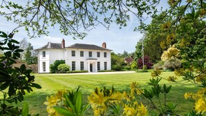 A large white building with a symmetrical facade, a central entrance, and a well-maintained lawn in front. - 6 Bed in West Malling (oc-n45282) (Kings Hill)