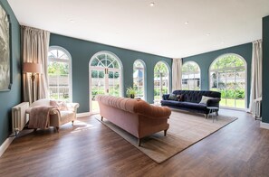 A spacious living room with a large window, a sofa, a chair, and a lamp.