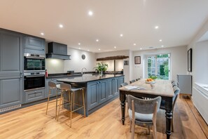 Una cocina moderna con armarios grises, una isla central con taburetes y un comedor con mesa y sillas de madera.