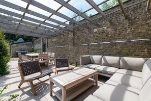 An outdoor patio with a wooden table, chairs, and a sofa.