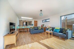 Ein modernes Wohnzimmer mit einer Couch, einem Couchtisch und einem Fernseher auf einem Holzboden.