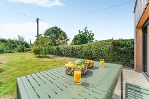 Ein Essbereich im Freien mit einem Tisch für zwei Personen, mit einer Obstschale und zwei Gläsern Orangensaft.