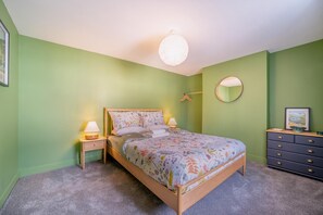 A bedroom with a bed, bedside tables, a dresser, a round mirror, and a hanging light fixture. - 2 Bed in Gatehouse Of Fleet (oc-n45274) (Gatehouse of Fleet)