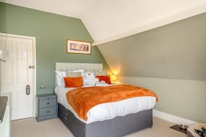 A bedroom with a bed, bedside tables, a lamp, and a framed picture on the wall.