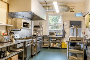 A commercial kitchen with stainless steel appliances, a large window, and a ventilation system.
