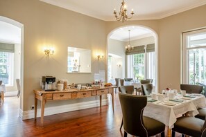 Un comedor con una mesa buffet de madera, sillas y una araña.