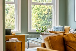Una habitación con sofá, una mesita y una ventana con vistas a zonas verdes.