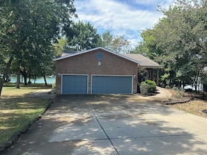 A two-car garage attached to a brick house with a covered porch.
