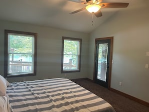 A bedroom with a bed, a ceiling fan, and three windows.