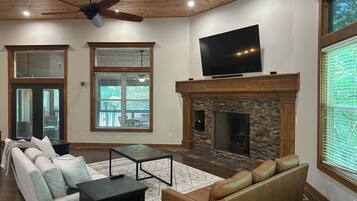 A living room with a fireplace, a television, and a large window.