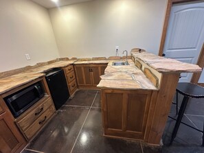 A kitchen with wooden cabinets, a built-in microwave, and a stone countertop.