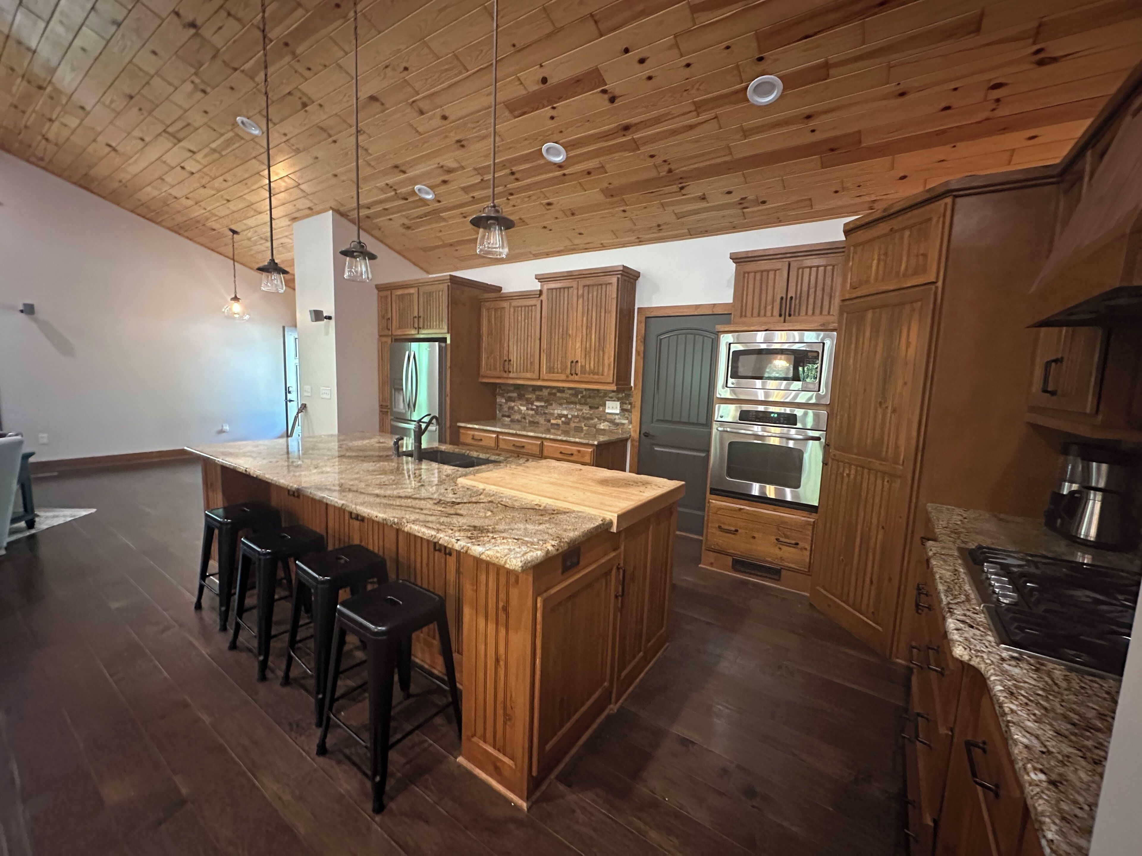 A kitchen with wooden cabinets, a granite countertop, and stainless steel appliances.