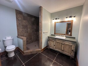 Een badkamer met een douche, toilet, wastafel en een spiegel met verlichting.