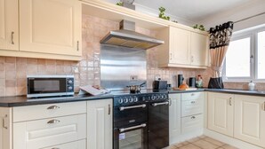 A kitchen with a microwave, stove, oven, and tiled backsplash. - 2 Bed in Middle Rasen (oc-c45686) (Middle Rasen)