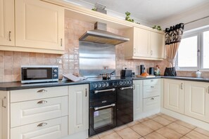 A kitchen with a microwave, stove, oven, and tiled backsplash. - 2 Bed in Middle Rasen (oc-c45686) (Middle Rasen)