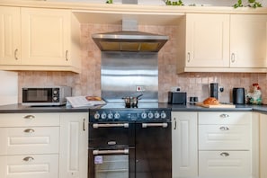 A kitchen with a stove, microwave, toaster, and a loaf of bread on the counter.