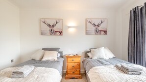 A bedroom with two beds, a nightstand, and two wall-mounted paintings of deer. - 2 Bed in Middle Rasen (oc-c45686) (Middle Rasen)