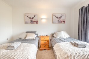 A bedroom with two beds, a nightstand, and two wall-mounted paintings of deer. - 2 Bed in Middle Rasen (oc-c45686) (Middle Rasen)