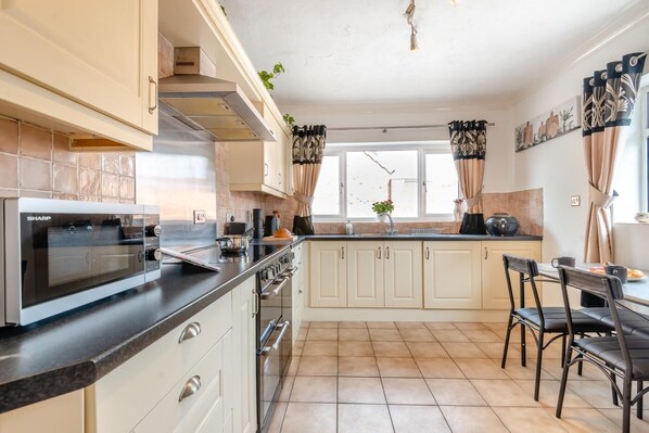 A kitchen with a built-in microwave, stove, and sink, with a dining area and large windows.