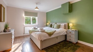 A bedroom with a bed, bedside tables, a window, and a green wall. - 3 Bed in Marden (oc-l45561) (Horsmonden)