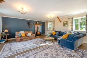 A living room with two sofas, a fireplace, and a large window with curtains.