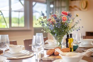 A dining table set with plates, glasses, and a centerpiece of flowers.