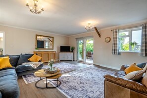 Ein Wohnzimmer mit Sofa, Sessel, Couchtisch und Fernseher.