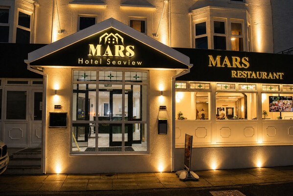 Un hotel llamado 'MARS Hotel Seaview' con una zona de recepción, un restaurante y una entrada bien iluminada.