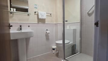 A bathroom with a glass-enclosed shower, a sink, and a toilet.