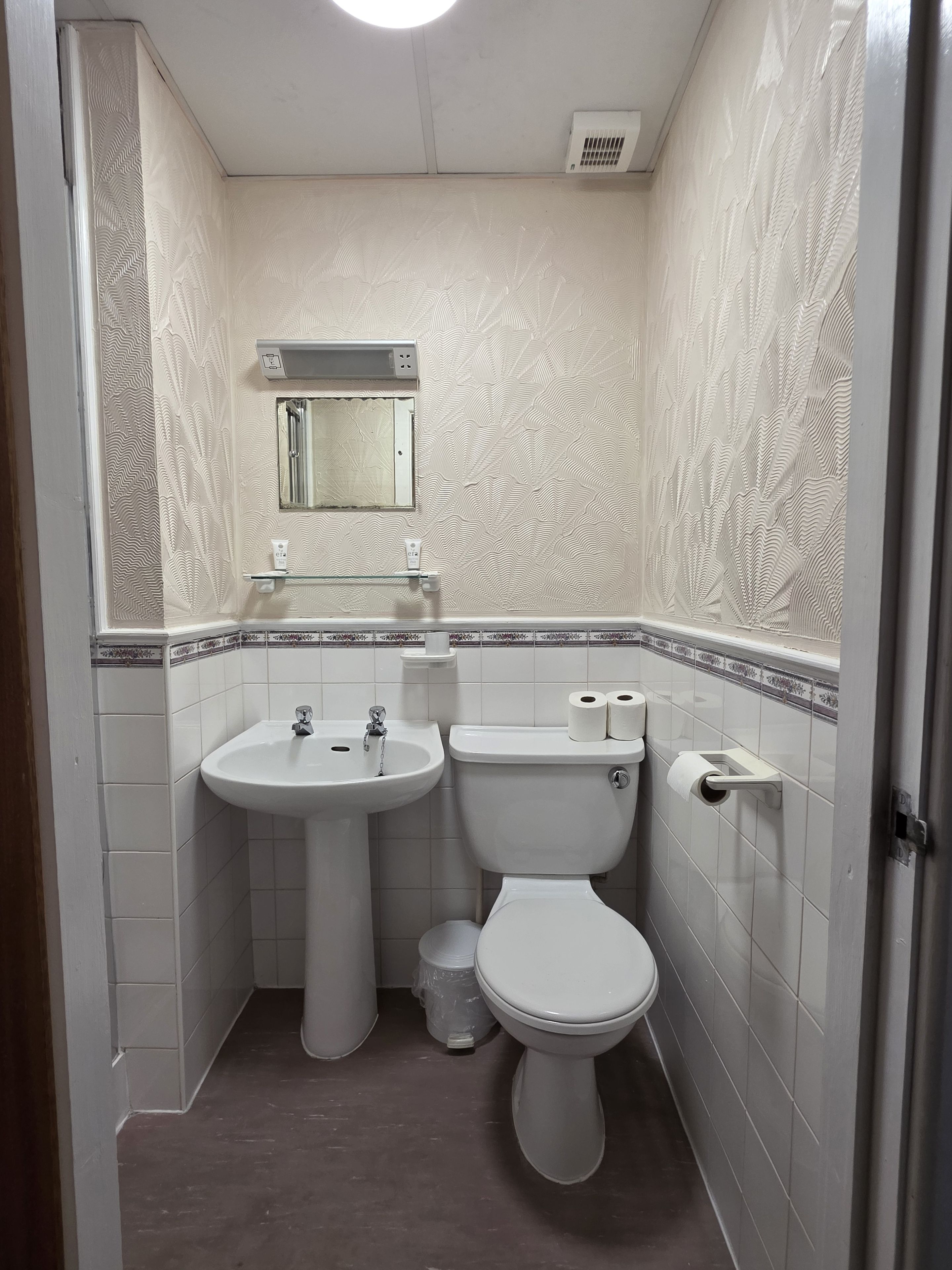 A bathroom with a white sink, toilet, and mirror.