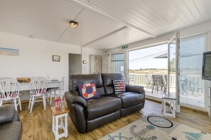 Ein gemütliches Wohnzimmer mit einer Ledersofa, weißen Stühlen, einem Esstisch und einem Balkon mit Blick.