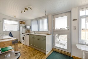Eine kleine Küche mit Waschmaschine, Spüle und Holztisch.