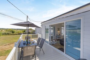 A covered outdoor area with a table set for dining, a chair, and a patio umbrella. - 3 Bed in Heacham (oc-v45689) (The Beach)