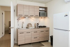 Eine Küche mit Holzschränken, einer Mikrowelle, einem Kühlschrank und einem Spülbecken.