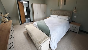 Ein Schlafzimmer mit Bett, Nachttischen, einem Kleiderschrank und einer Bank.