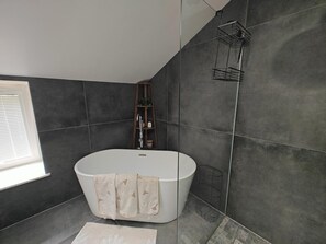 Um banheiro moderno com uma banheira de pé, um porta-toalhas e uma prateleira com artigos de higiene pessoal.
