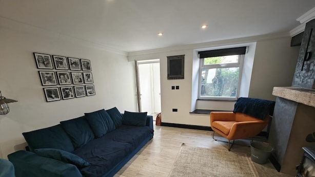 Ein Wohnzimmer mit Sofa, Stuhl, Teppich, Kamin und Fenster mit Blick.