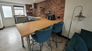 Eine moderne Küche mit Holztisch, Barhocker und Backsteinwand.