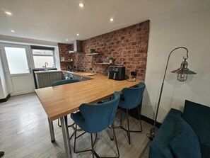 Eine moderne Küche mit Holztisch, Barhocker und Backsteinwand.