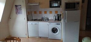 A compact kitchen with a dishwasher, washing machine, microwave, and a sink. - Charm and comfort** for a family vacation in La Bourboule (La Bourboule)