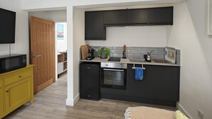 A modern kitchen with black cabinets, a microwave, a kettle, and a toaster. - 1 Bed in Brixham (oc-f45535) (Brixham)
