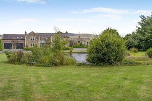 A residential property with a pond, stone buildings, and a grassy lawn. - 4 Bed in Wharton (oc-h45870) (Wharton)