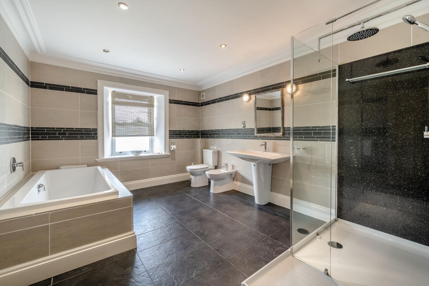 Ein modernes Badezimmer mit Badewanne, Toilette, Bidet und einer Duschkabine.