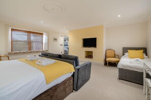 A hotel room with a bed, a sofa, a TV mounted on the wall, and a chair. - 4 Bed in Wharton (oc-h45870) (Wharton)
