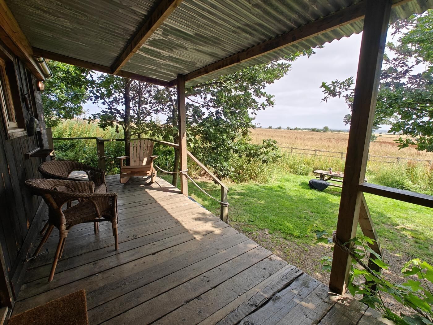 A wooden deck with wicker furniture and a view of a field.