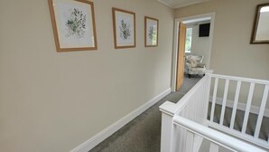 A hallway with a white railing, beige walls, and three framed botanical prints. - 3 Bed in Grizebeck (oc-b45345) (Kirkby Ireleth)